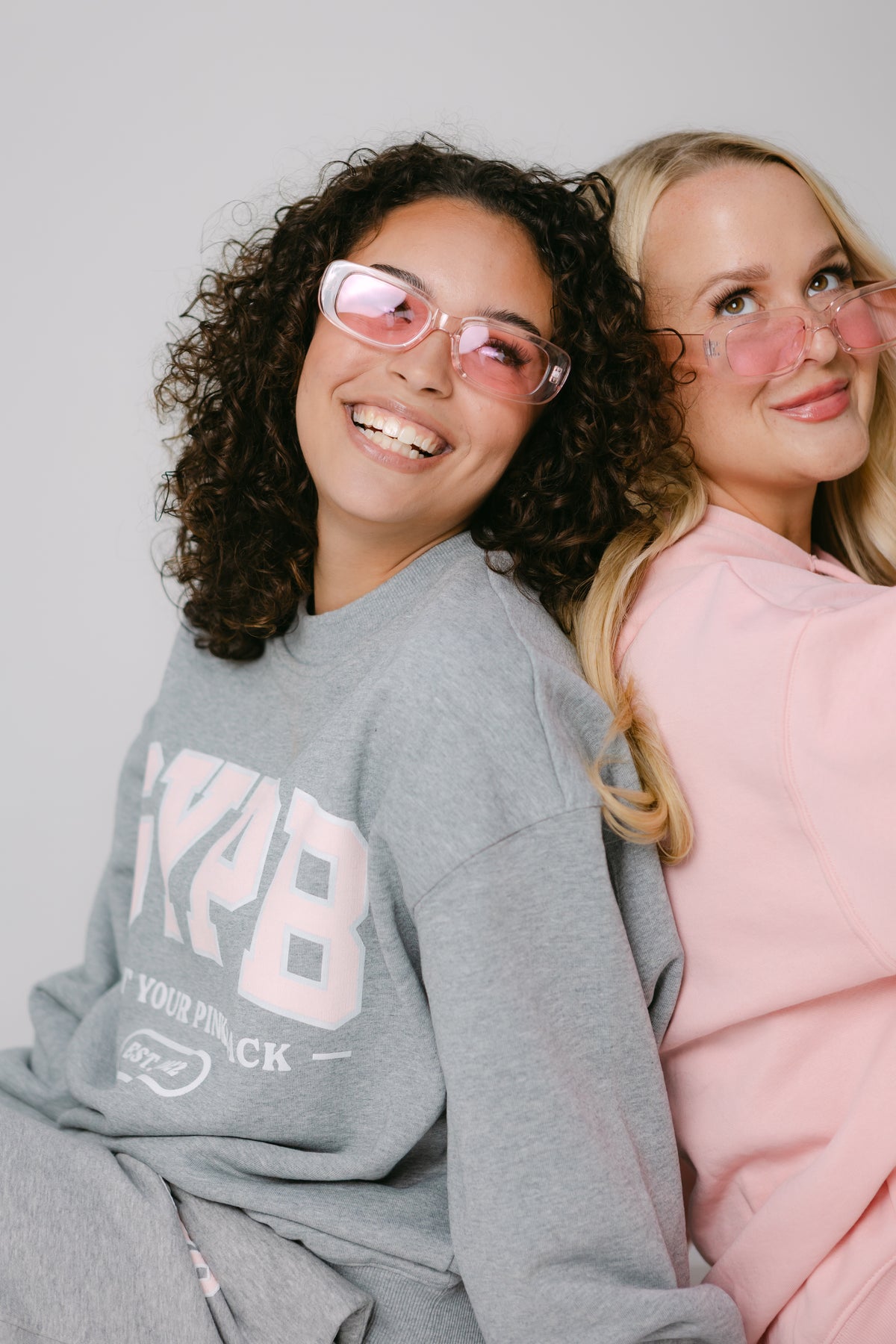 Two women in pink sunglasses and GYPB sweatshirts